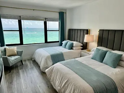 two beds in a hotel room with a view of the ocean at Directly on the Beach with Pool & Ocean View in Miami Beach