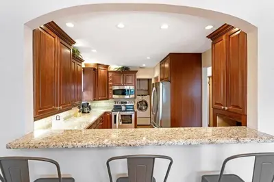 a kitchen with wooden cabinets and a marble counter top at DOWNTOWN LAS OLAS WATERFRONT HOME UPDATED UNIT in Fort Lauderdale