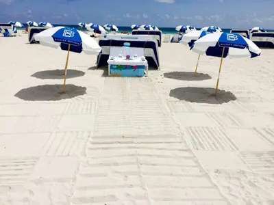 a group of blue and white umbrellas on the beach at CasaGrandeSouthBeach by AmericanVacationLiving 6BR in Miami Beach