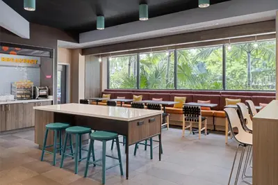 a restaurant with green stools and a large window at Tru By Hilton Miramar in Miramar