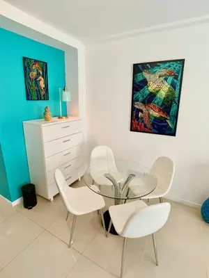 a dining room with a glass table and white chairs at Directly on the Beach with Pool & Ocean View in Miami Beach