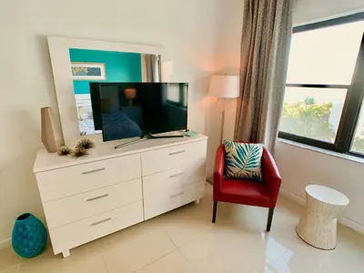 a white dresser with a tv and a red chair at Directly on the Beach with Pool & Ocean View in Miami Beach