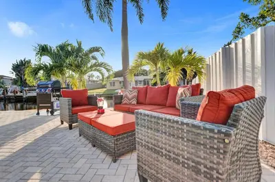 a patio with couches and tables and palm trees at Gorgeous poolhome on the canal in Fort Lauderdale