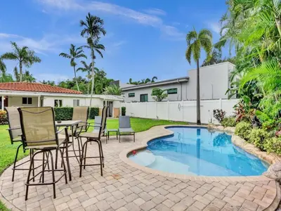 a patio with a table and chairs next to a swimming pool at 3 min. walk to Wilton Drive, pool and huge yard in Fort Lauderdale