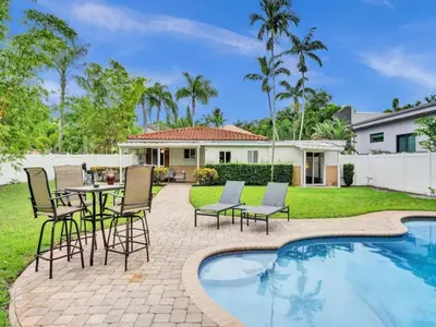 a backyard with a table and chairs next to a swimming pool at 3 min. walk to Wilton Drive, pool and huge yard in Fort Lauderdale