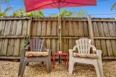 two chairs and an umbrella next to a fence at Private studio, 5 min. walk to Wilton Drive in Fort Lauderdale