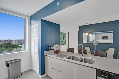 a kitchen with a sink and a blue wall at Awesome Ocean View Modern Condo Pool Shuttle in Hallandale Beach