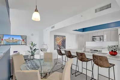 a white kitchen with a glass table and chairs at Awesome Ocean View Modern Condo Pool Shuttle in Hallandale Beach