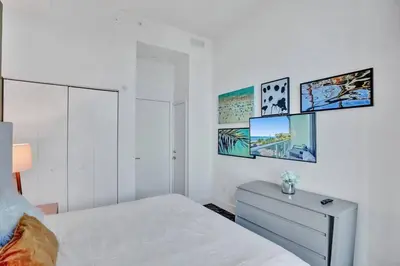 a white bedroom with a bed and a dresser at Oceanfront Condo Direct Ocean View Beach Access in Hollywood