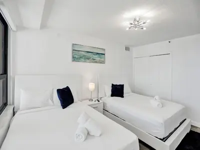 two beds in a room with white walls at Beautiful condo in resort beach service 1004 in Miami Beach