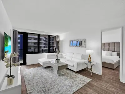 a living room with white furniture and a large window at Adorable 2 Bedroom Condo Beach Service 605 in Miami Beach