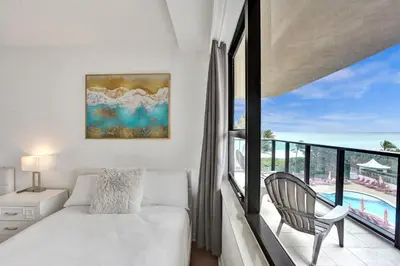 a bedroom with a bed and a balcony with a pool at Spacious Ocean View Resort Beach Condo 601 in Miami Beach
