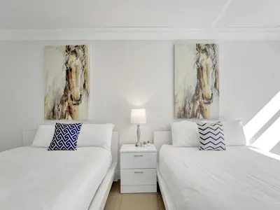 a white bedroom with two beds and a picture of a horse on the wall at Cozy Miami Beach Condo Beach Service 407 in Miami Beach