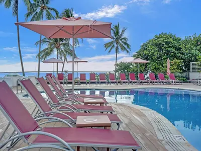a pool with chairs and umbrellas next to the water at Ocean View Beach Retreat Beach Service 606 in Miami Beach