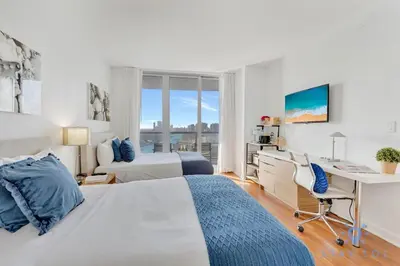 a white bedroom with a desk and a bed at Beachwalk - Sun, Amazing Pools and Gym in Hallandale Beach