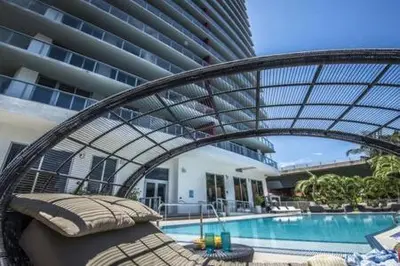 a bed in front of a building with a swimming pool at Beachwalk - Sun, Amazing Pools and Gym in Hallandale Beach