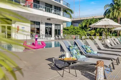 a pool with chaise lounge chairs and a table and a swimming pool at Apartment with Balcony - Pool- Near Beach in Hallandale Beach