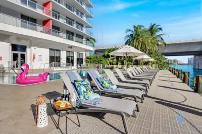 a row of chaise lounge chairs next to a pool at Apartment with Balcony - Pool- Near Beach in Hallandale Beach