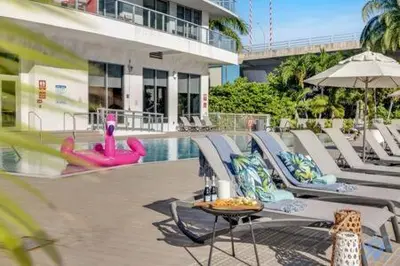 a swimming pool with lounge chairs and a table and an umbrella at Spectacular Apartment with Balcony Near Beach in Hallandale Beach
