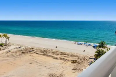 a view of a beach with palm trees and the ocean at Beachfront Resort Pool Ocean View Balcony Gym in Aventura