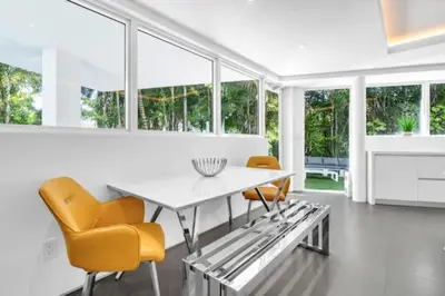 a dining room with a white table and yellow chairs at Villa Loggia Oasis Luxurious 6BD ,7BA with Resort Style Pool in Golden Beach