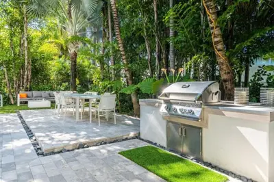a backyard with a grill and a table with chairs at Villa Loggia Oasis Luxurious 6BD ,7BA with Resort Style Pool in Golden Beach