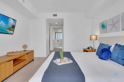 a bedroom with a bed with a tray of fruit on it at Modern 2 BR - Beachwalk Resort - Pool - Gym in Hallandale Beach