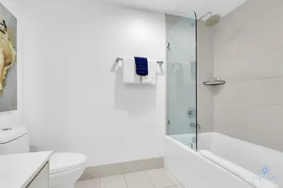 a white bathroom with a shower and a toilet at Modern 2 BR - Beachwalk Resort - Pool - Gym in Hallandale Beach