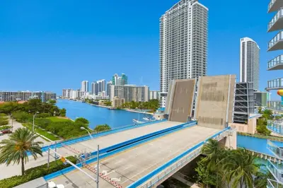 a bridge over a river in a city with tall buildings at Modern 2 BR - Beachwalk Resort - Pool - Gym in Hallandale Beach