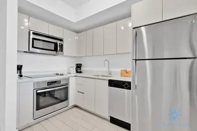 a white kitchen with a refrigerator and a microwave at Modern Condo - Amazing Pool - Gym - Balcony in Hallandale Beach