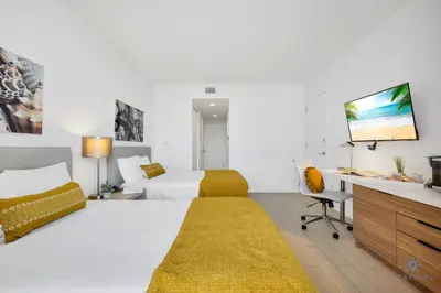 a bedroom with two beds and a desk and a tv at Modern Condo - Amazing Pool - Gym - Balcony in Hallandale Beach