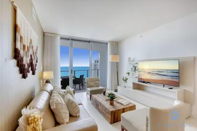 a living room with a couch and a large screen tv at Oceanfront Elegance - Sunset Views, Pet-Friendly in Hollywood