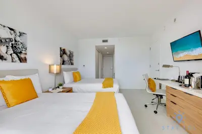 a hotel room with a bed and a desk with a computer at Resort Amenities - Amazing Pool and Gym in Hallandale Beach