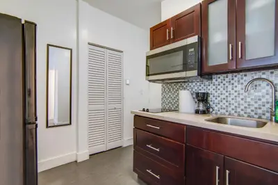 a kitchen with wooden cabinets and a sink and a mirror at Comfy 1 B/R, Near Ocean Dr & Beach - South Beach in Miami Beach