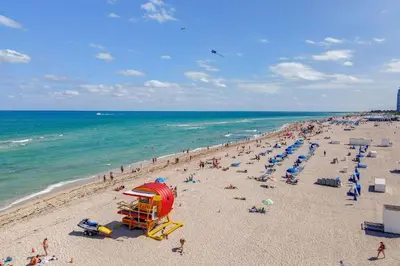 a beach with a bunch of people on the sand and the ocean at 2B/2B, Free Parking, South Beach, 1 Block 2 Beach in Miami Beach