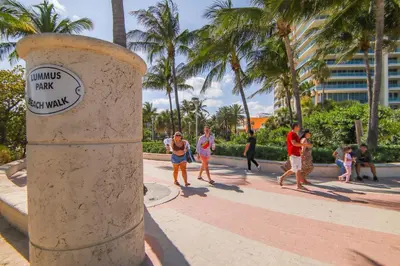 a group of people walking on a sidewalk with palm trees at South Beach 2BR with Private Balcony, Walk to Beach in Miami Beach