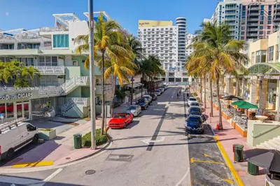 a street with palm trees and cars on a city street at Beachfront 1 bedroom with 2 Queen Beds on Ocean Drive in Miami Beach