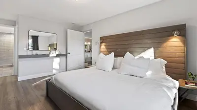 a bedroom with a large bed with a wooden headboard at Hot Tub Firepit Deck 10mins to Beach Near Las Olas Middle Terrace Cottage by AvantStay in Fort Lauderdale