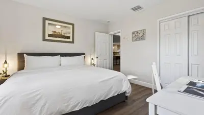 a bedroom with a large white bed and a desk at Hot Tub Firepit Deck 10mins to Beach Near Las Olas Middle Terrace Cottage by AvantStay in Fort Lauderdale