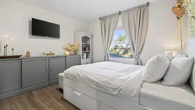 a white bedroom with a bed and a window at Hot Tub Firepit Deck 10mins to Beach Near Las Olas Middle Terrace Cottage by AvantStay in Fort Lauderdale