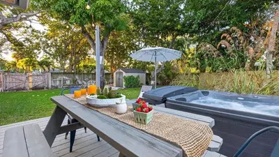 a picnic table with fruit and an umbrella next to a hot tub at Hot Tub Firepit Deck 10mins to Beach Near Las Olas Middle Terrace Cottage by AvantStay in Fort Lauderdale
