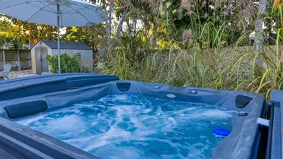 a hot tub in a yard with an umbrella at Hot Tub Firepit Deck 10mins to Beach Near Las Olas Middle Terrace Cottage by AvantStay in Fort Lauderdale