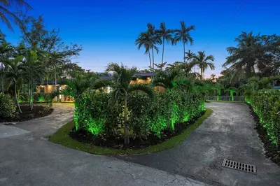 a driveway with green plants and palm trees at VillaKOBO Heated pool Spa Golf Tennis crocodile in Miami
