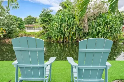 two blue chairs sitting on the grass next to a pond at VillaKOBO Heated pool Spa Golf Tennis crocodile in Miami