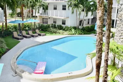 a swimming pool with lounge chairs and a resort at Suites at Coral Resorts in Miami