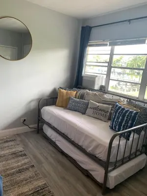 a bed in a room with a mirror and a window at Walk to the beach, Studio, with Pool and FREE Parking in Hallandale Beach