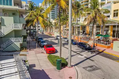 a red car parked on a street with palm trees at Deco Ocean Dr Deal, w/2 Queen Beds, South Beach in Miami Beach
