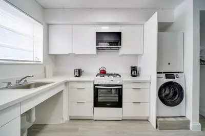 a white kitchen with a stove and a dishwasher at Deco Beachside Apt, w/2 Queen Beds, Washer/Dryer in Miami Beach