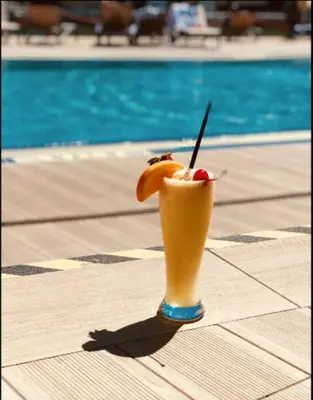 a drink sitting on a table next to a pool at Sunny Mornings & 2 Full Beds, BeachWalk Studio in Hallandale Beach
