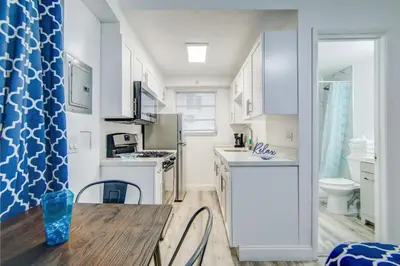 a kitchen with white cabinets and a table with chairs at Balcony Deco Apt, w/2 QueenBeds, on Ocean Dr Beach in Miami Beach